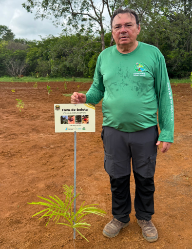 Colaborador da Germinare apresentando sinalização de área sob plano de manejo sustentável e recuperação de vegetação nativa.